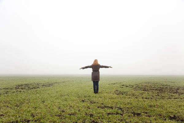 Menina no campo de primavera no tempo de nevoeiro . — Fotografia de Stock