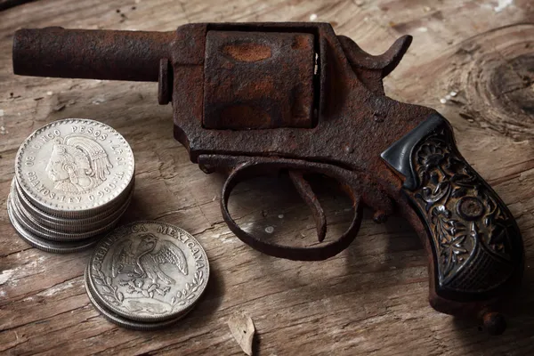 Револьвер и мексиканские монеты — стоковое фото