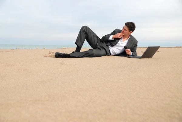 Бізнесмен лежить на пляжі Стокове Зображення