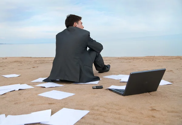 Бизнесмен сидит на пляже Лицензионные Стоковые Фото
