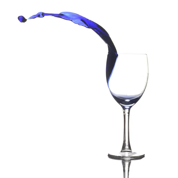 stock image Colored liquid splashing out a glass on a white background