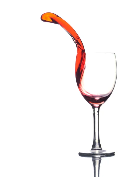 stock image Colored liquid splashing out a glass on a white background