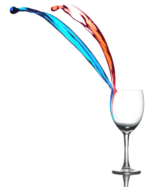 Stock image Colored liquid splashing out a glass on a white background