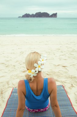 Close-up of woman seating on the beach with flowers in her hair looking to the sea clipart