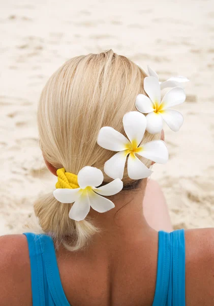 Close-up de mulher sentada na praia com flores no cabelo olhando para o mar — Fotografia de Stock
