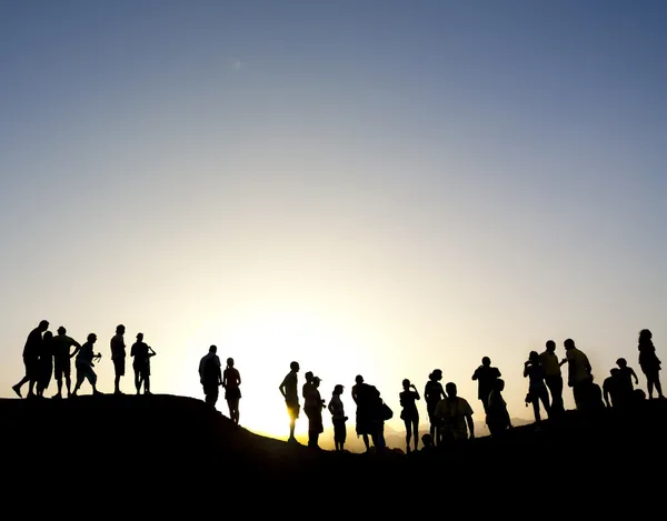 Группа силуэтов против солнца на вершине горы — стоковое фото