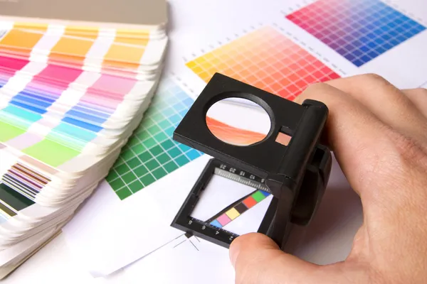 Sosteniendo un lupe y examinando colores —  Fotos de Stock