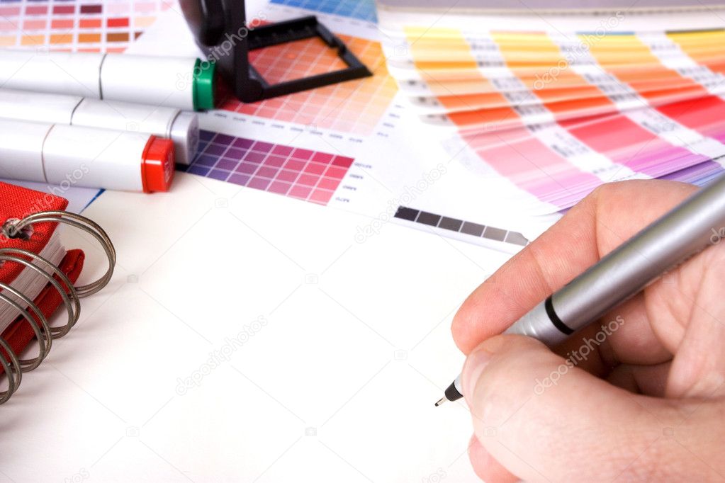 Designer surrounded by design colour swatches and pens with blank paper
