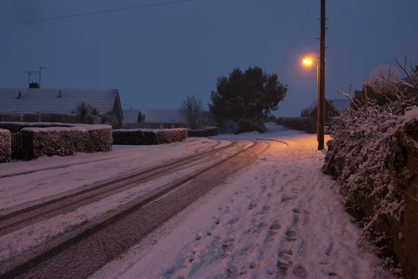 stock image Snowfall on a road at dusk in winter in the uk