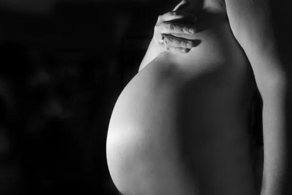 Беременная женщина на черном фоне — стоковое фото