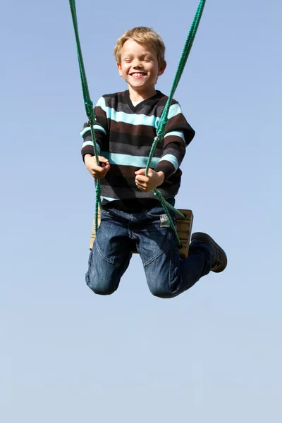 Joyeux enfant riant sur une balançoire — Photo