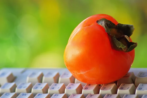 A fruit caqui on keyboard. — Stock Photo, Image