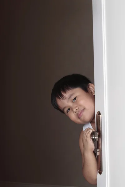Junge lugt hinter Tür hervor — Stockfoto