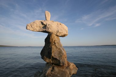 Cross, rocks stacked one one top of another on beach clipart