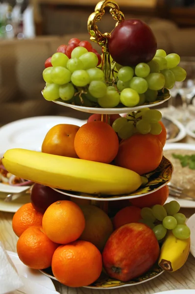 stock image Assorted fresh fruit including bananas, tangerines, apples, grapes and pears sitting in a plate