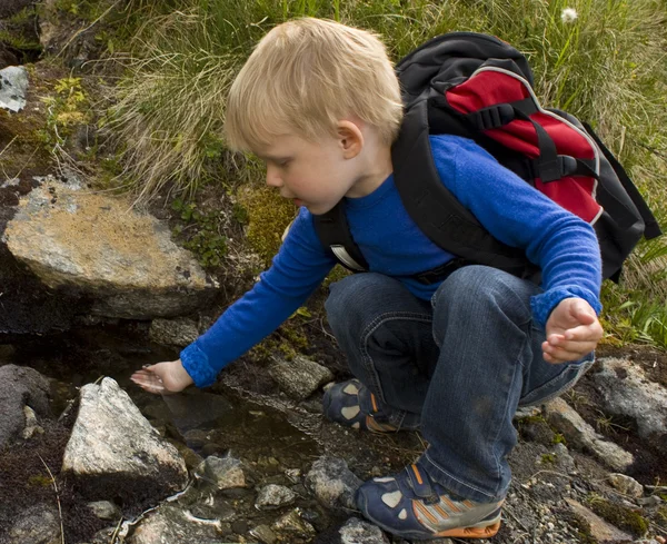 Мальчик пьет воду из источника — стоковое фото