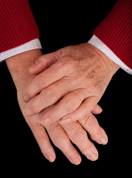 stock image Arthritic hands of a senior woman on a black background.