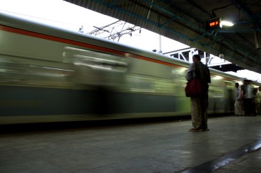 Bir banliyö treni bir Hint tren istasyonu platformu gelmesi için bekleyen.