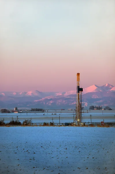 Amanhecer cedo com uma plataforma de petróleo e montanhas rochosas — Fotografia de Stock