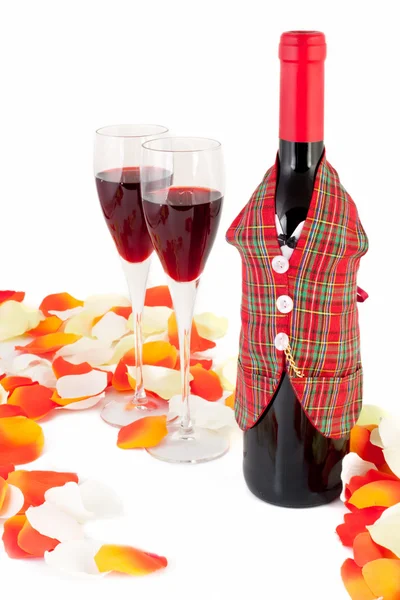 ワイングラスと白い背景で隔離のバラの花びらと赤ワインのボトル — ストック写真