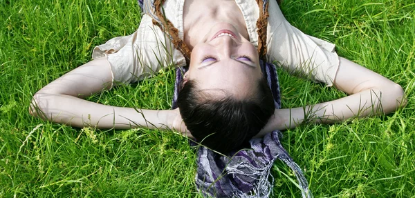 Mladá žena ležící na trávě — Stock fotografie