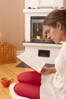 Young woman in front of a fireplace clipart