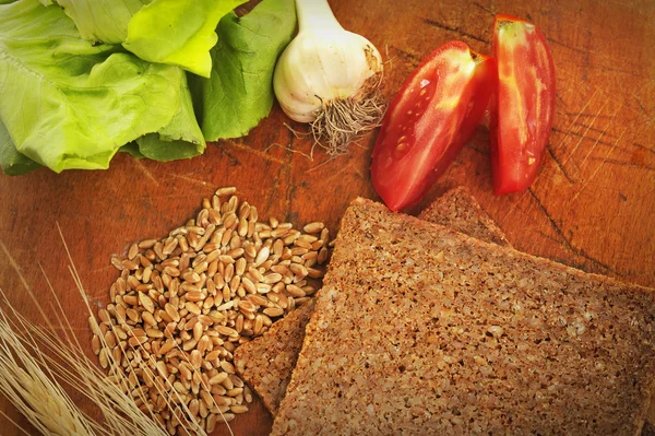 Pão integral fatiado e legumes — Fotografia de Stock