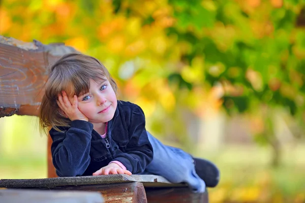 Маленькая девочка лежит на скамейке — стоковое фото