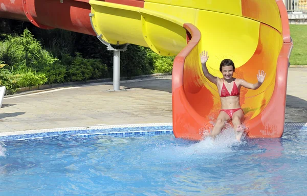 Menina desce o slide para a piscina — Fotografia de Stock