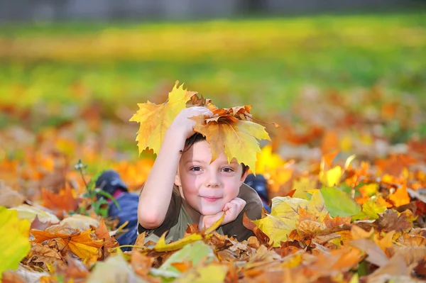 Kind spielt mit Blättern Stockbild