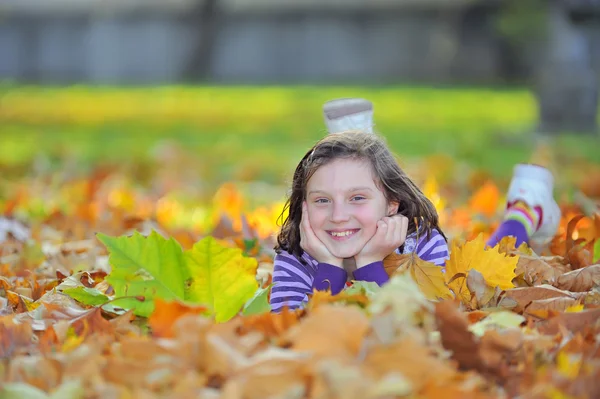 Маленька дівчинка лежить на осінньому листі — стокове фото