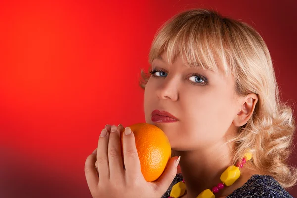 Portrait woman with orange on a red — Stock Photo, Image