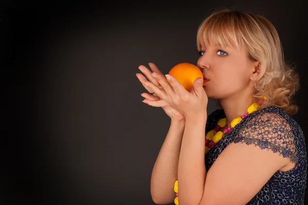 Жінка з апельсином на чорному — стокове фото