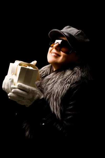 Donna con cappello e cappotto indossando guanti e tenendo in mano un regalo — Foto Stock