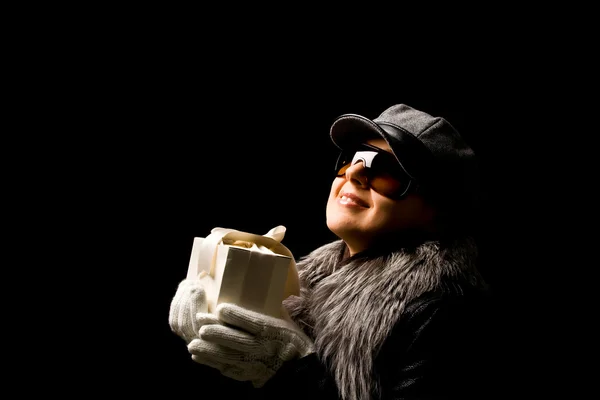 Woman with hat and coat wearing gloves and holding a present — Stock Photo, Image