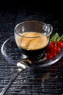 Photo of espresso coffee with currants on black glasstable clipart