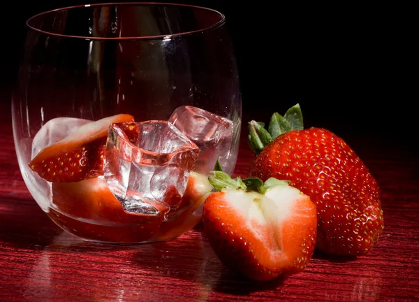 赤いテーブル上の氷の上でイチゴの写真 — ストック写真