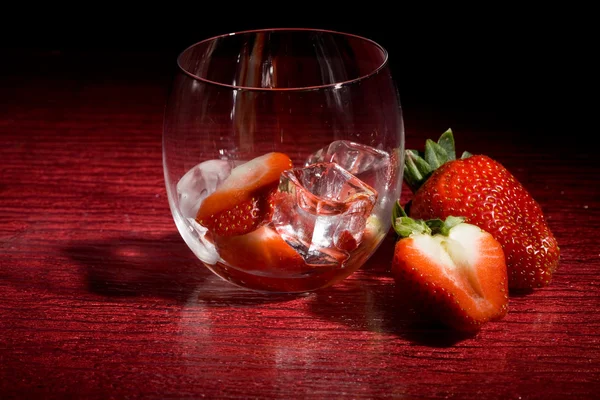 Jordgubbar på is på röd bakgrund - cocktail efterrätt — Stockfoto