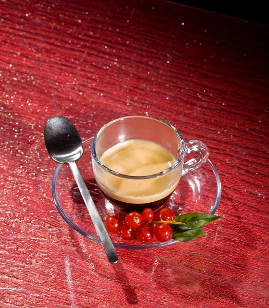 Espresso coffee with currants on red glasstable Royalty Free Stock Images