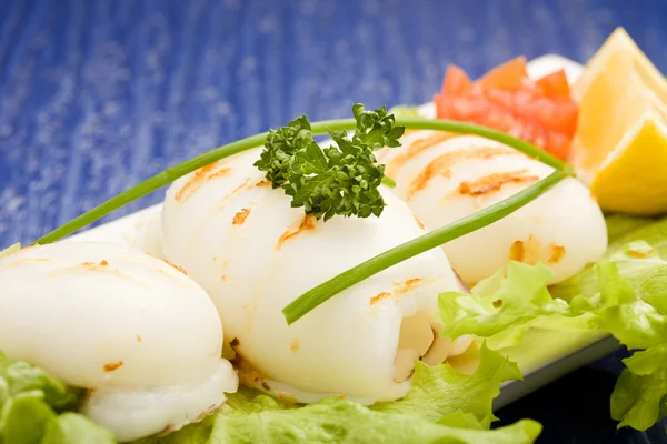 Squid with lettuce on blue glasstable — Stock Photo, Image