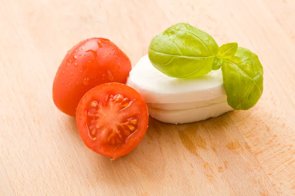 Tomate e Mozzarella na placa de corte — Fotografia de Stock
