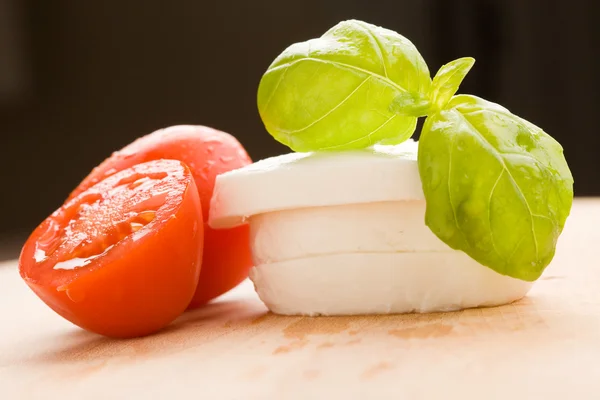 Tomate e Mozzarella na placa de corte — Fotografia de Stock