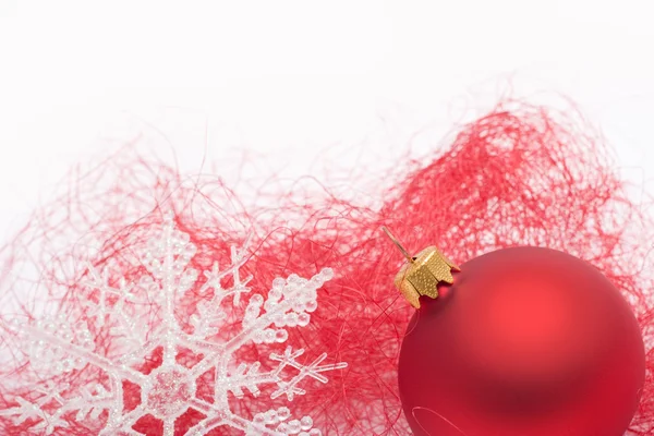 Красная рождественская безделушка и снежинка — стоковое фото