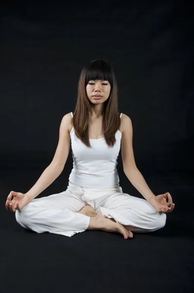 Menina asiática realizando ioga com fundo escuro — Fotografia de Stock