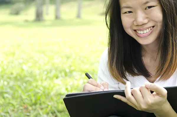 使用钢笔和笔记本 Whilte 学习室外的亚洲女孩 — 图库照片