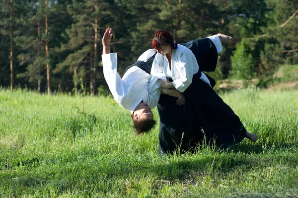 Zwei junge Männer trainieren im Aikido in Holz lizenzfreie Stockfotos