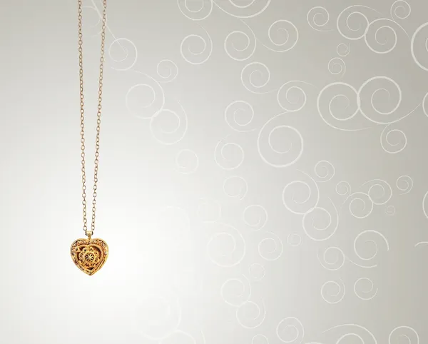 Золотой кулон в форме сердца на фоне кудрей — стоковое фото