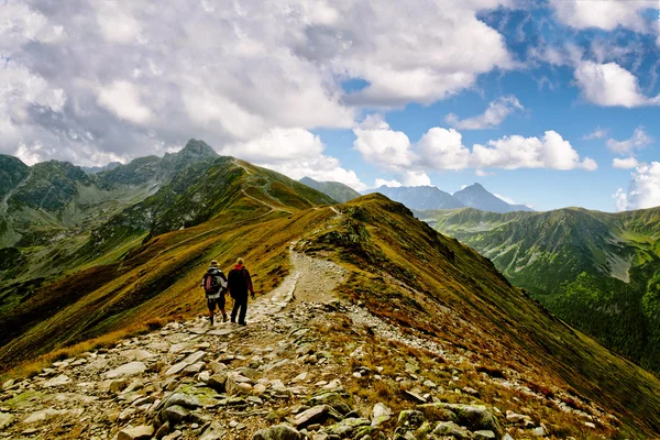 两个男子爬山陡峭的小山与背包和洛基山视图 — 图库照片