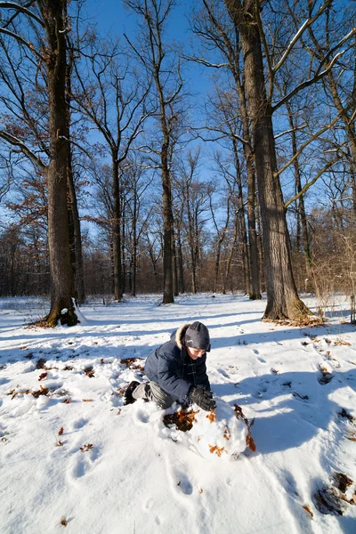 森の近く雪で遊んでいる幸せなかわいい少年 — ストック写真