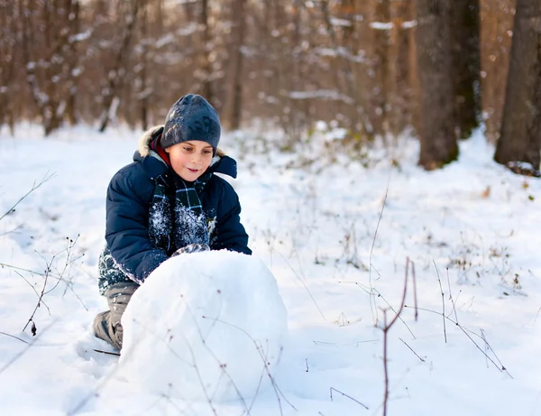 Criança feliz brincando na neve — Fotografia de Stock